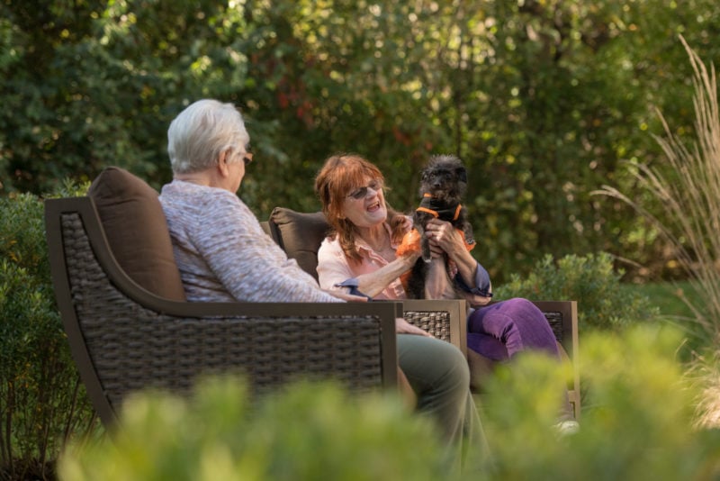 Two women sitting outdoors with a dog
