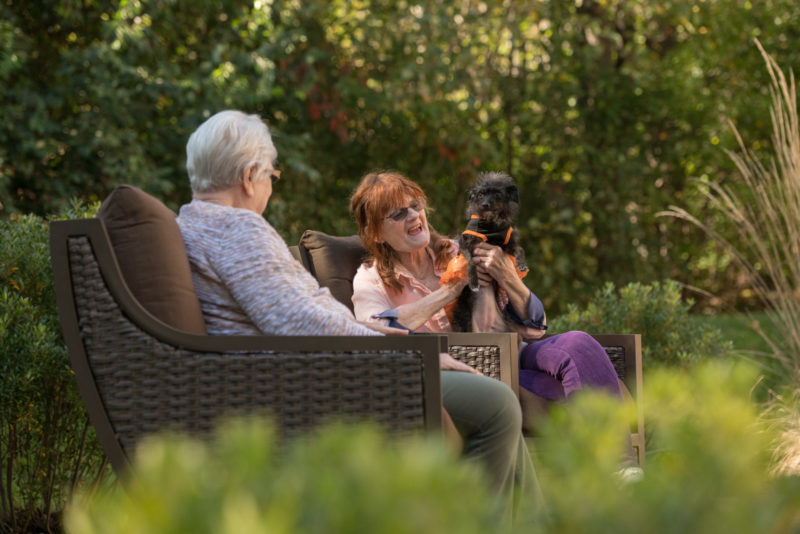 Two women sitting outdoors with a dog