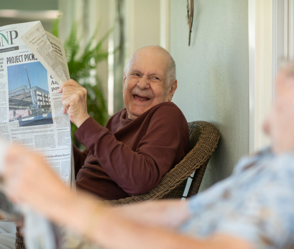 Male resident smiling holding a newspaper